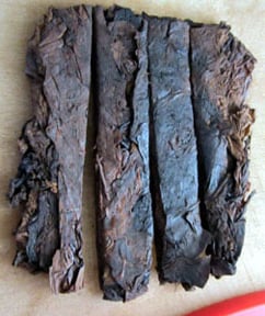 Four dark, rectangular plugs of tobacco with visible leaf textures.