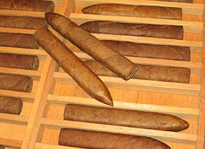 A light wooden rectangular cigar mold holding multiple cigars in grooves.